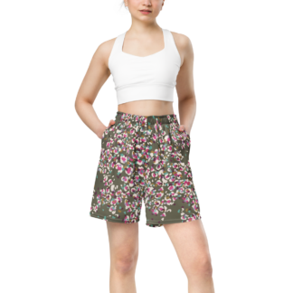 Bermuda short large unisexe en coton imprimé “Léopard kaki” de Paradis Perdus® porté surtaillé et taille haute par une femme vue de face les mains dans les poches